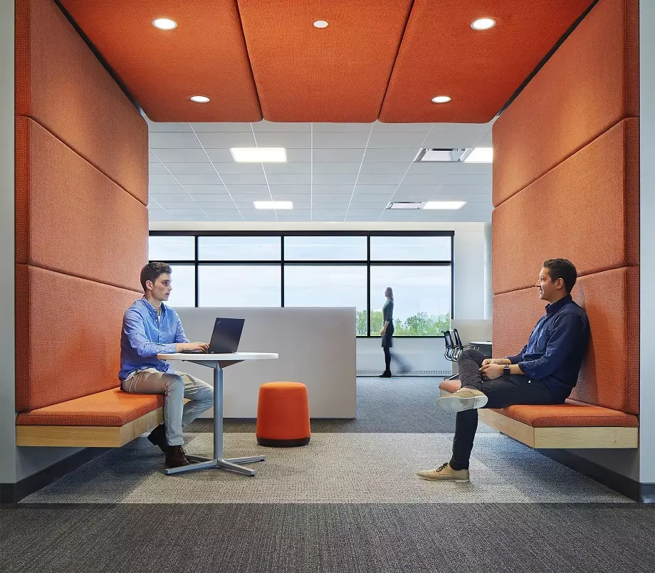 Two people talking and using their laptops